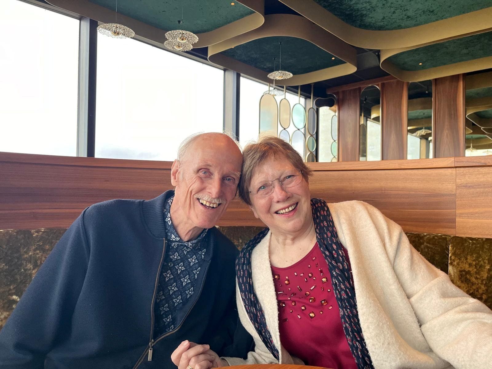 Een man in een blauwe trui en een vrouw in een rode jurk met de hoofden tegen elkaar.