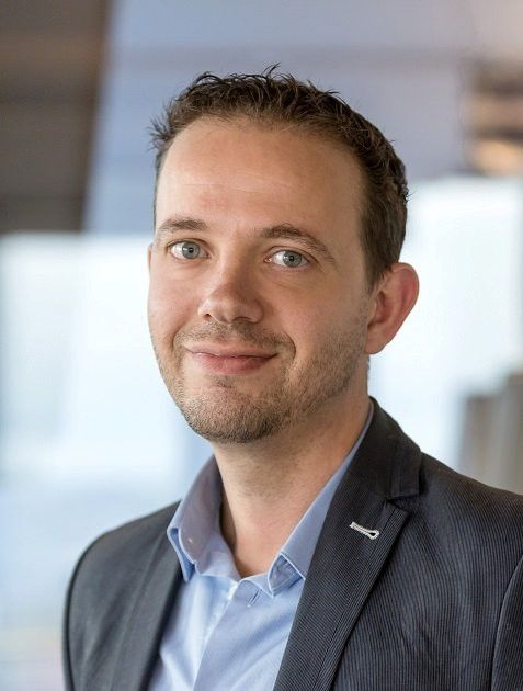 Man met een donkerblauw pak en een lichtblauw overhemd. 