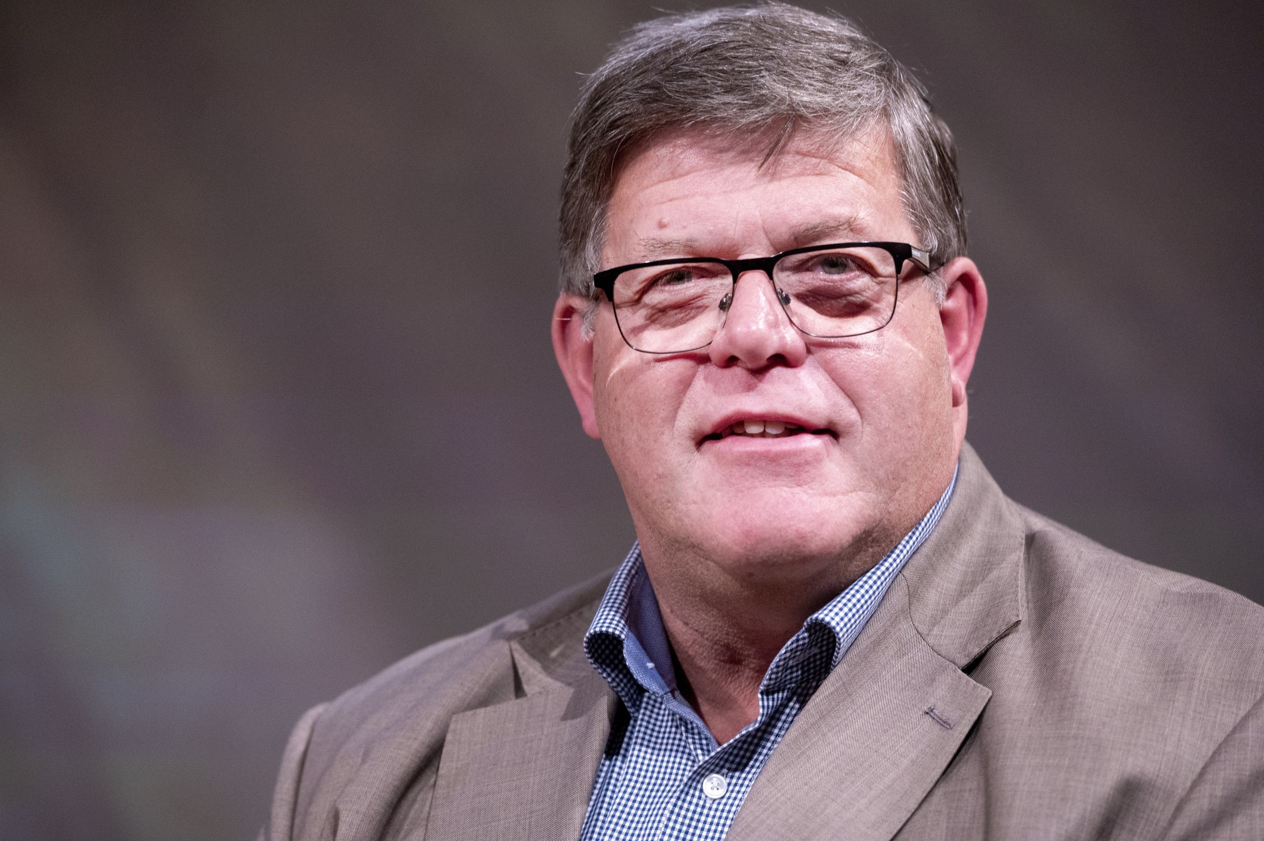 Oudere man met licht grijzend haar en bril.