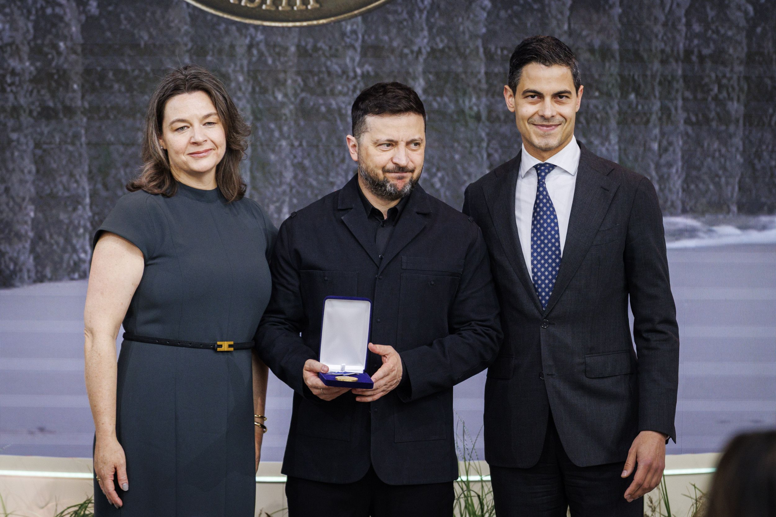 Een man in zwarte kleding laat een medaille zien.
