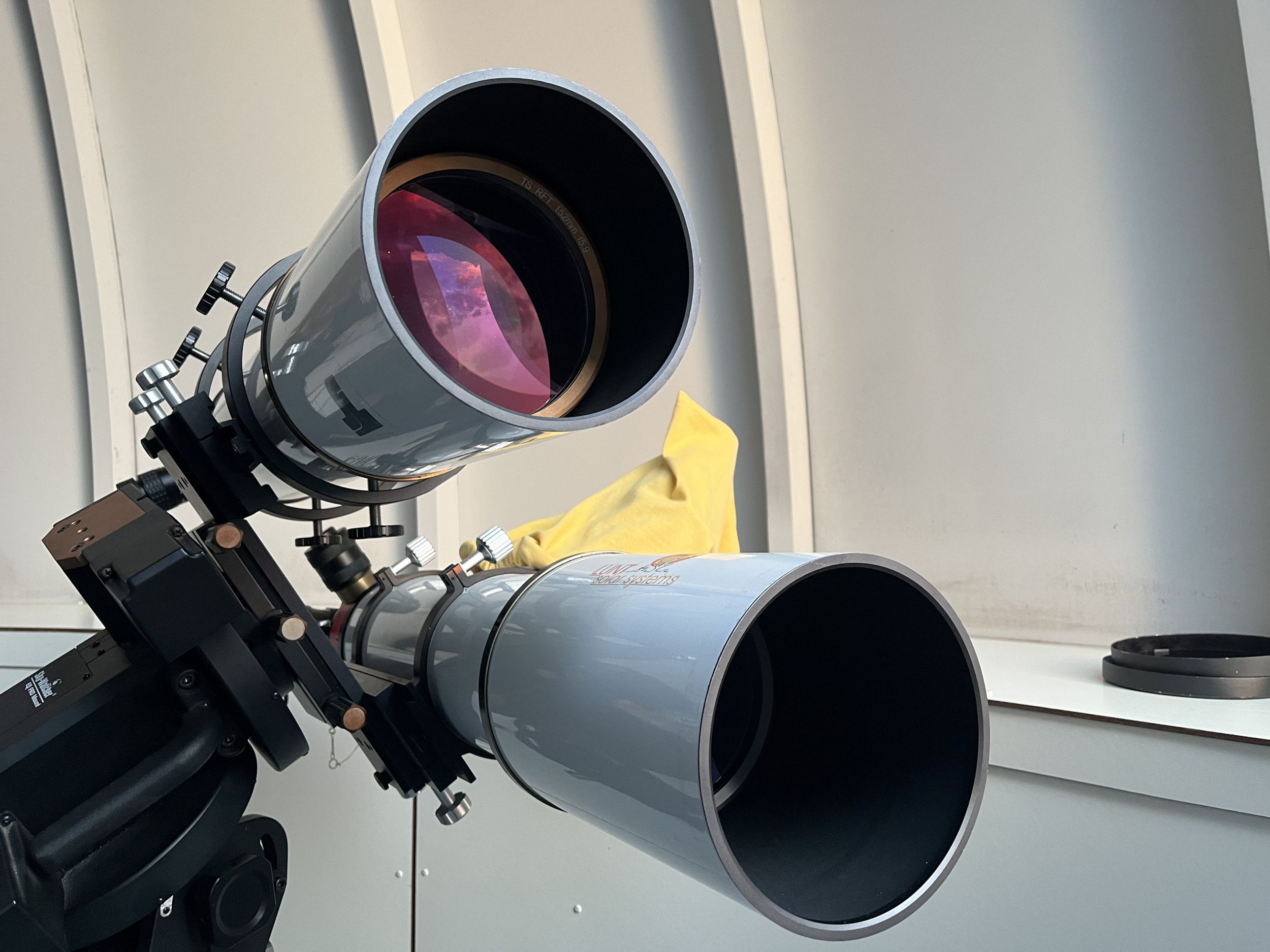 Foto van een dubbele telescoop op een standaard.