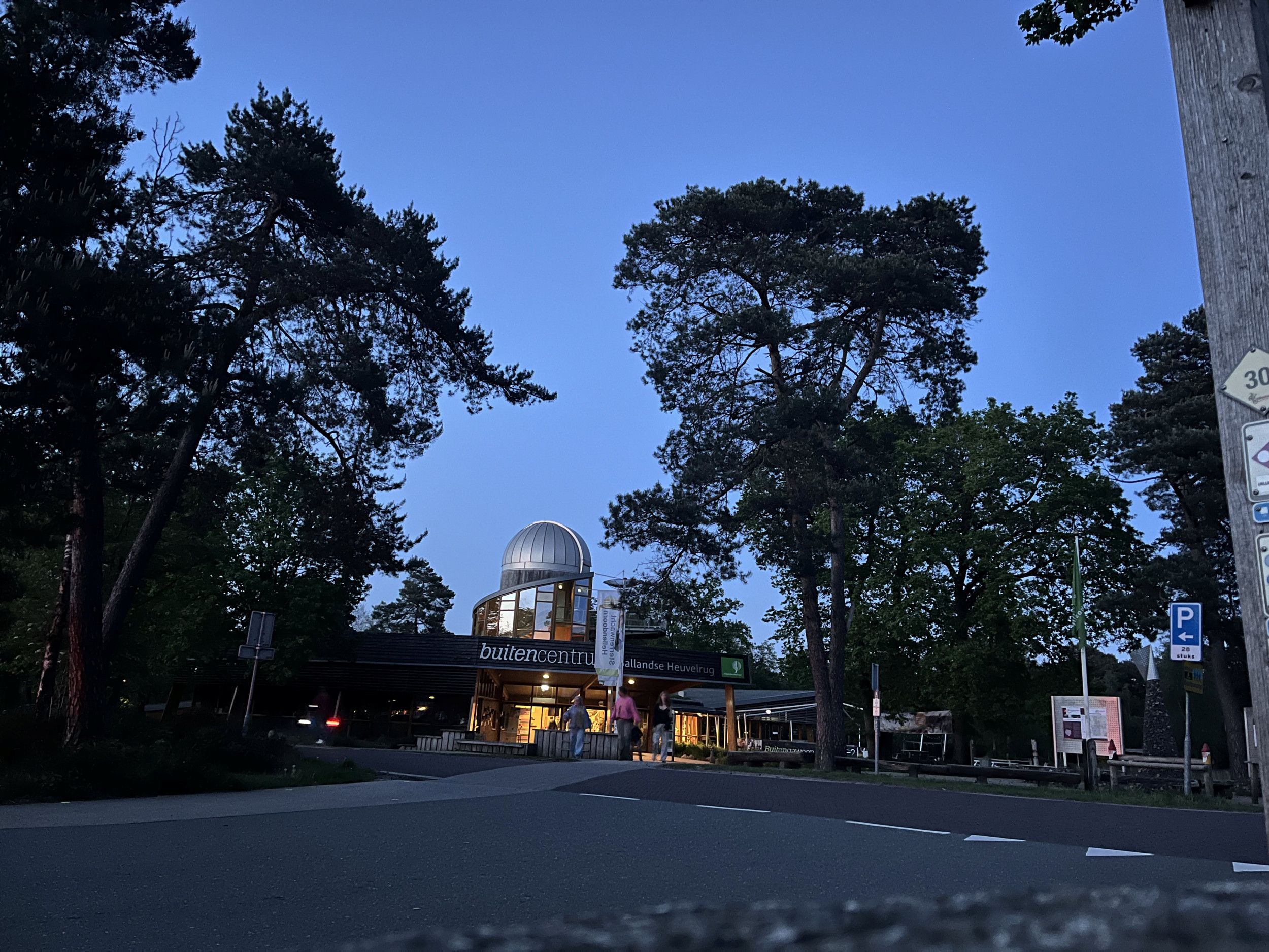 Foto van een houte gebouw met daarop een koepel, omringd met naaldbomen.