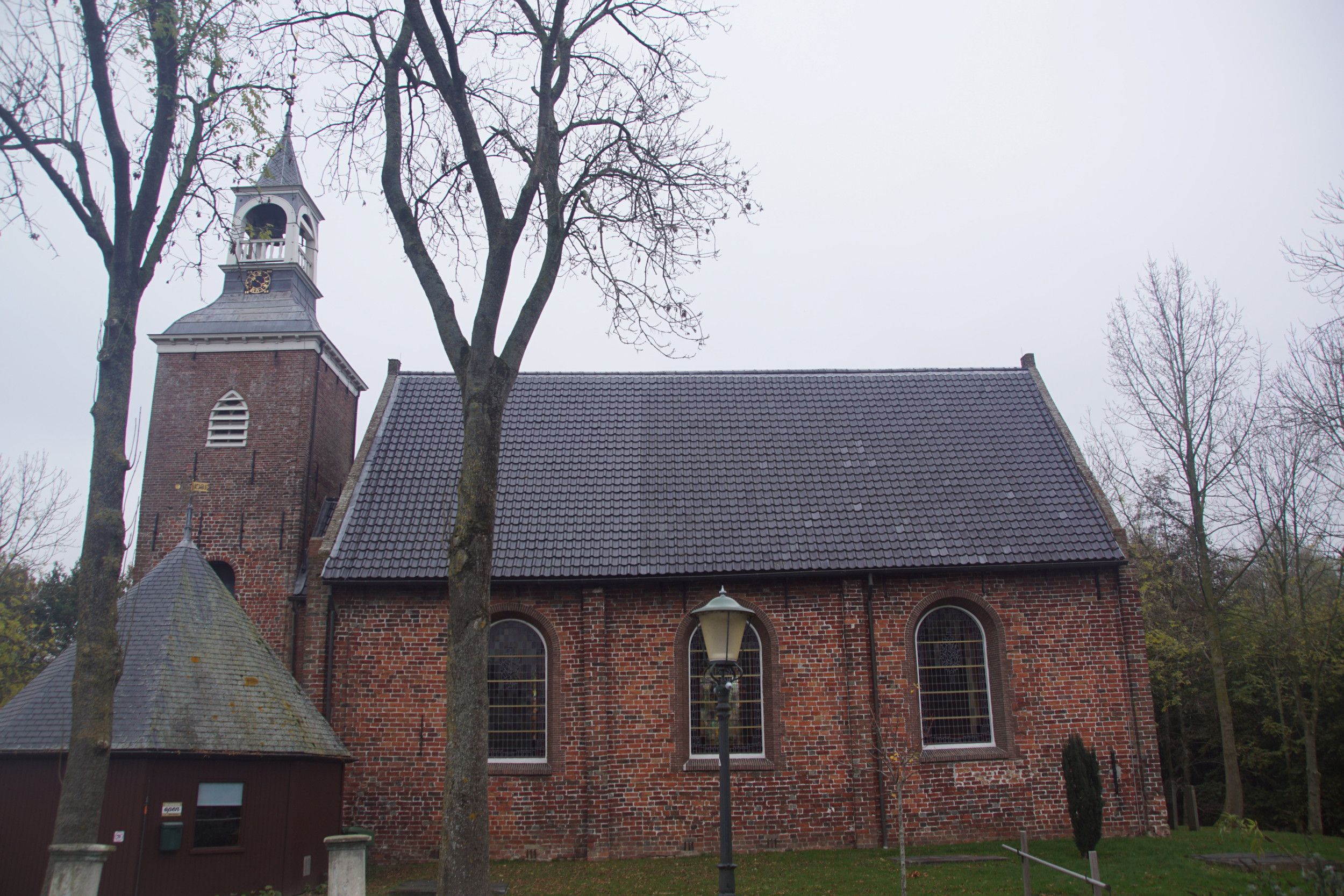 Een oud kerkgebouw, met links de toren.