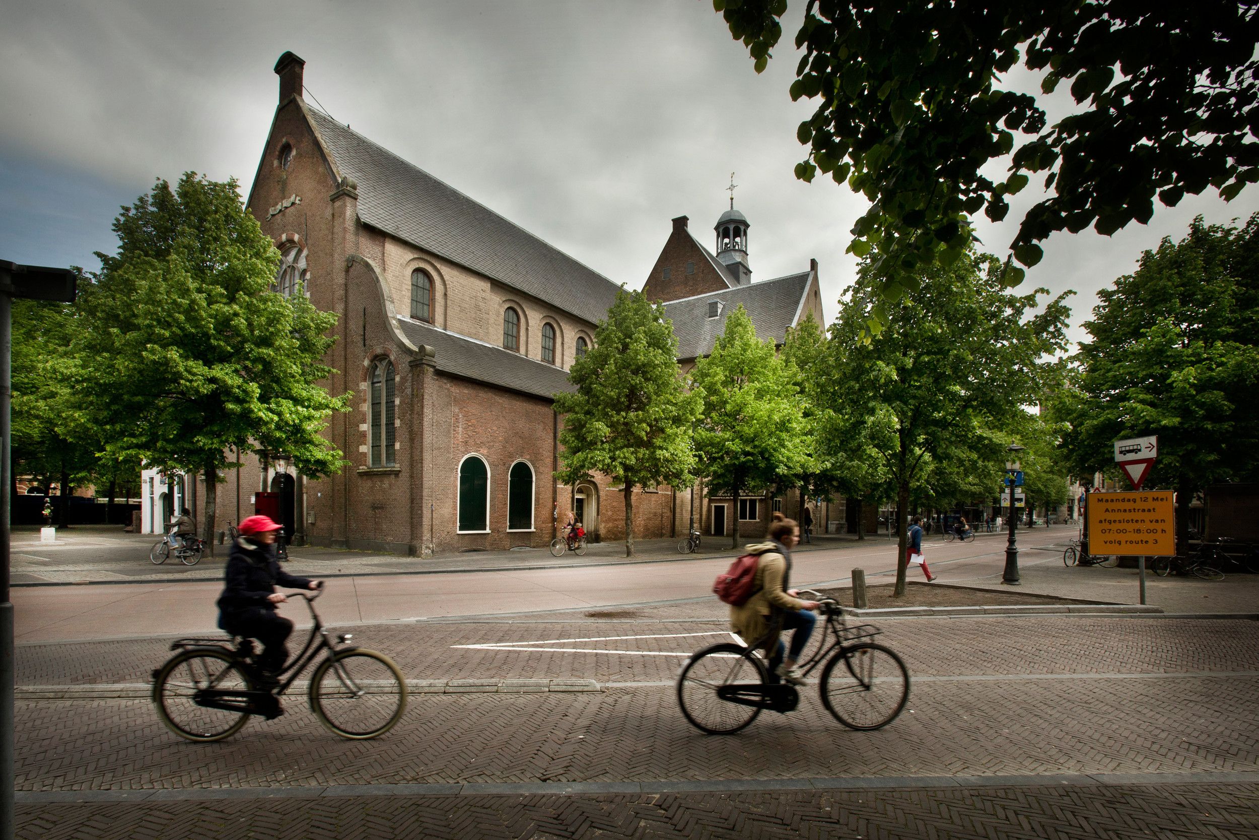 Een oudere kerk, midden in de stad. Op de voorgrond twee fietsers.