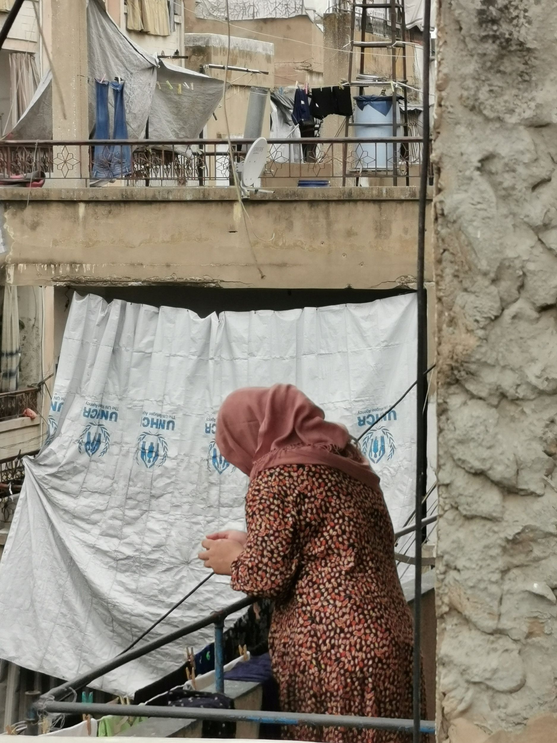 Een oude vrouw staat op een balkon.
