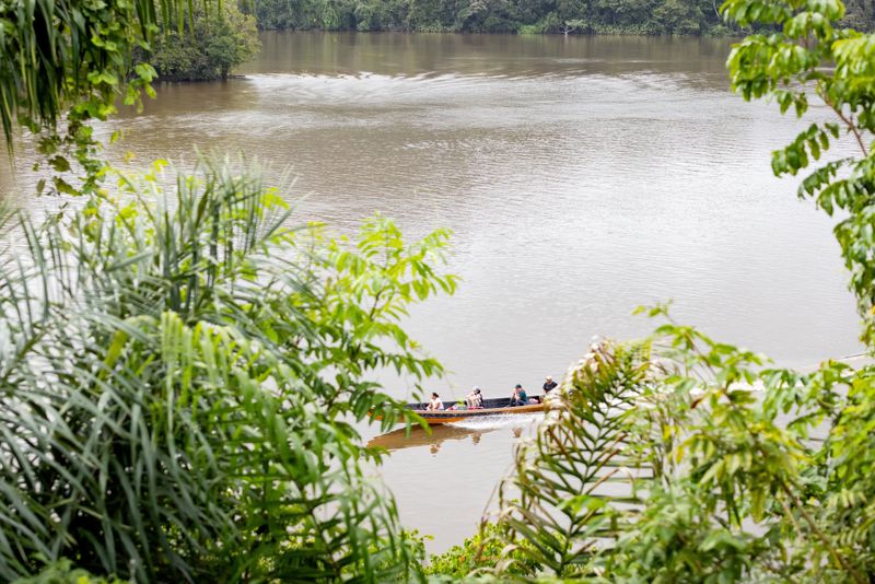 Boomstamboot vaart over de brede rivier.